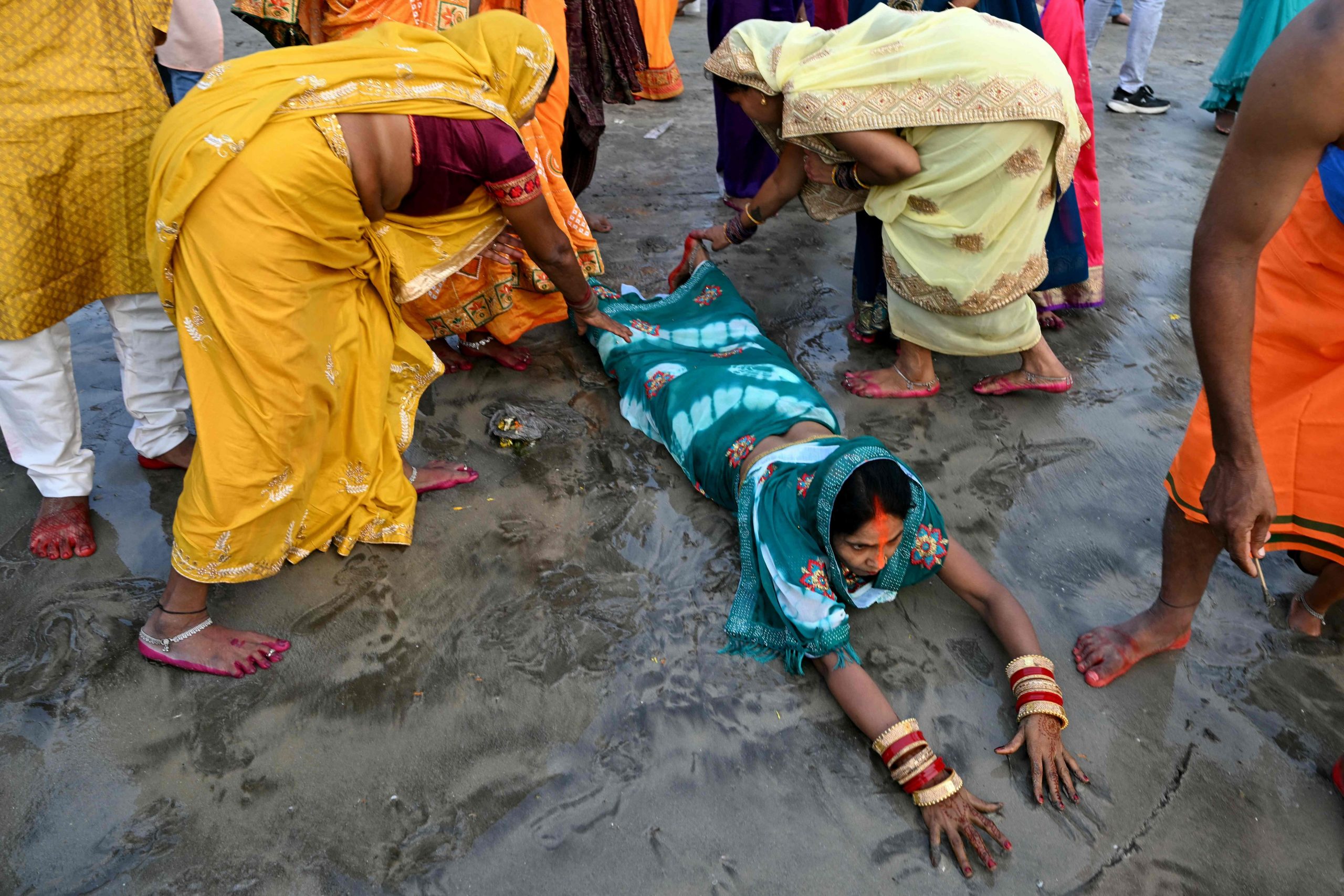 During Sunday's Chhath Puja at Mumbai's Juhu beach, worshippers touch each other's feet in a show of respect as one devotee lowers herself to the ground and offers prayers to the Sun god. (AFP)